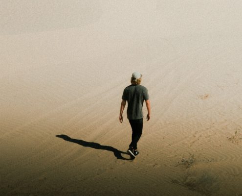 Man walking alone in the desert pondering unanswerable questions