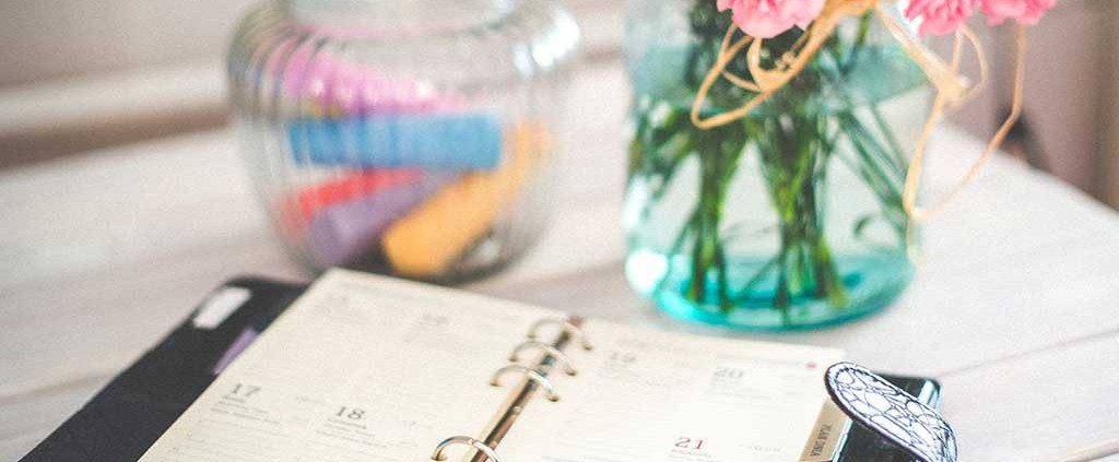 A calendar book sitting next to flowers