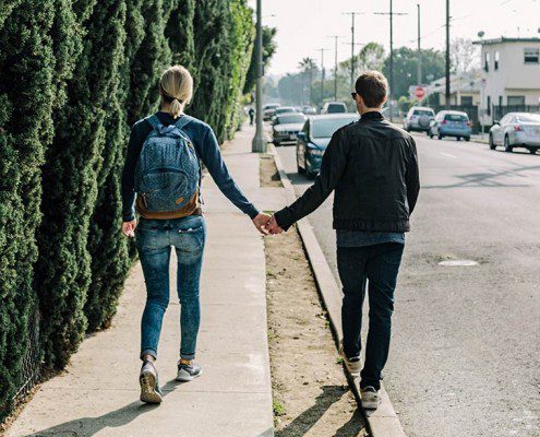 Couple holding hands walking along the sidewalk