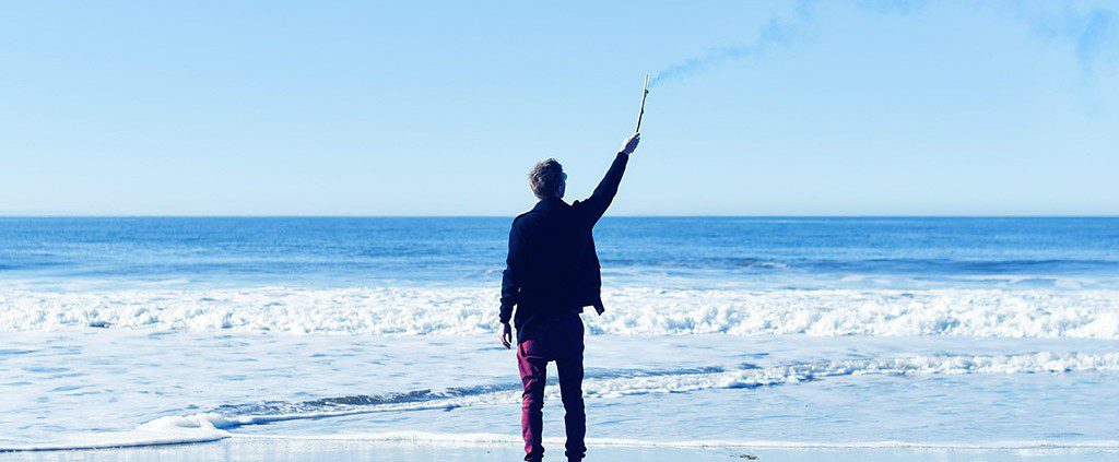 Guy with a flare on the beach contemplating life as a single male.