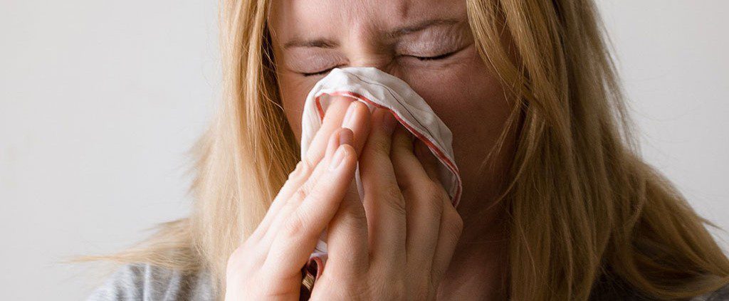 Woman blowing her nose into a tissue - blessed to be sick