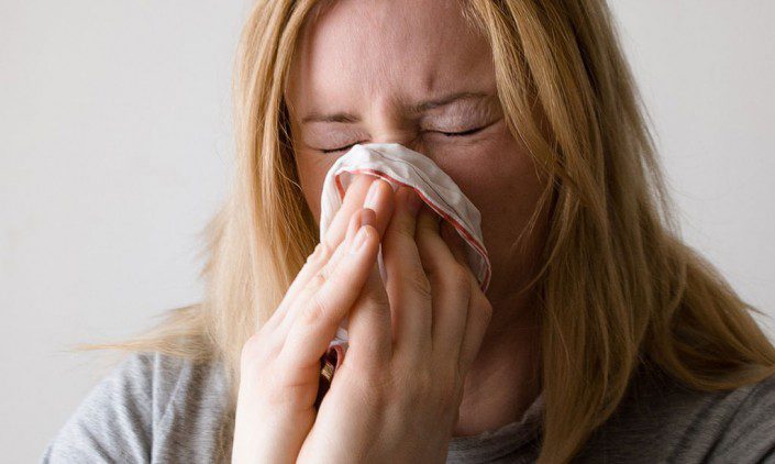 Woman blowing her nose into a tissue - blessed to be sick