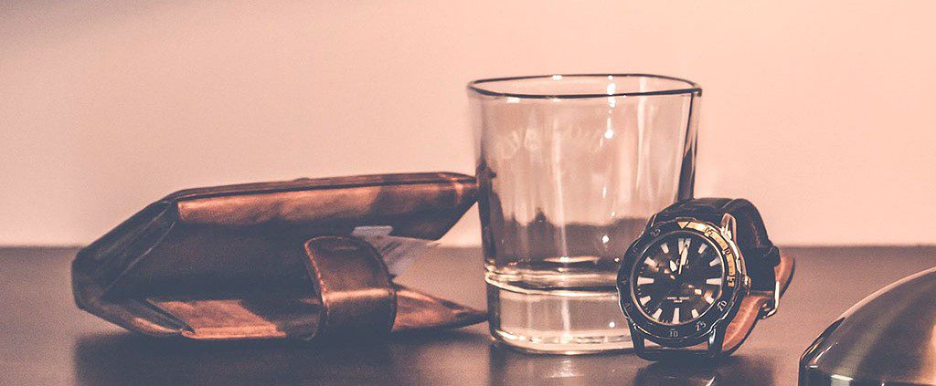 Watch, whiskey glass and wallet on the table - freedom from financial woes