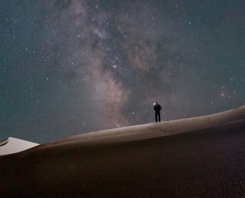 Man alone in field with galaxy