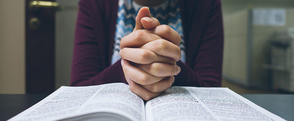 Woman praying in peace with her hands on the bible