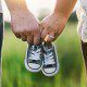 Couple holding hands and a pair of baby shoes