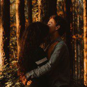Couple hugging against a tree in the woods