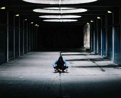 Person sitting alone in the middle of an empty parking garage