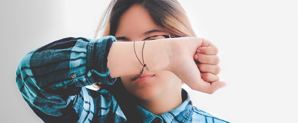 Girl holding her forearm over her face