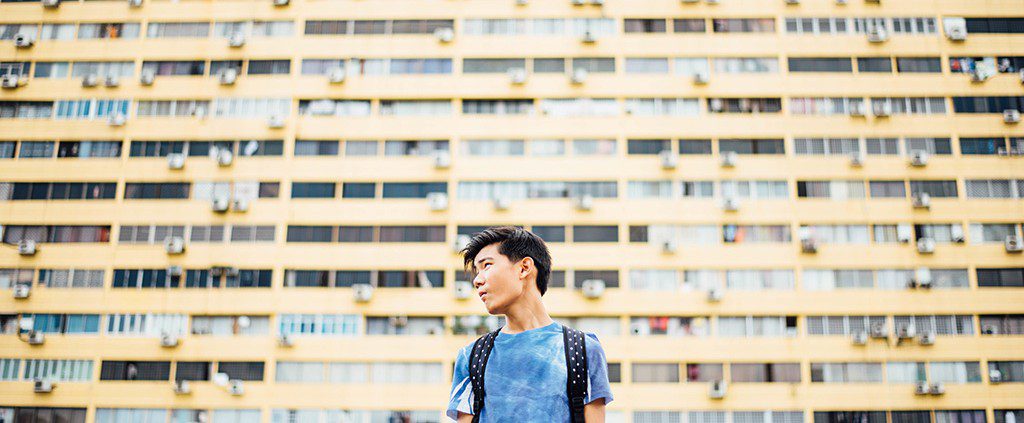 Young man standing in front of an apartment building