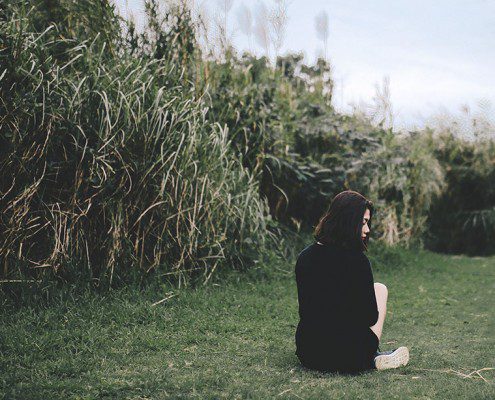 Girl sitting alone in a grassy field