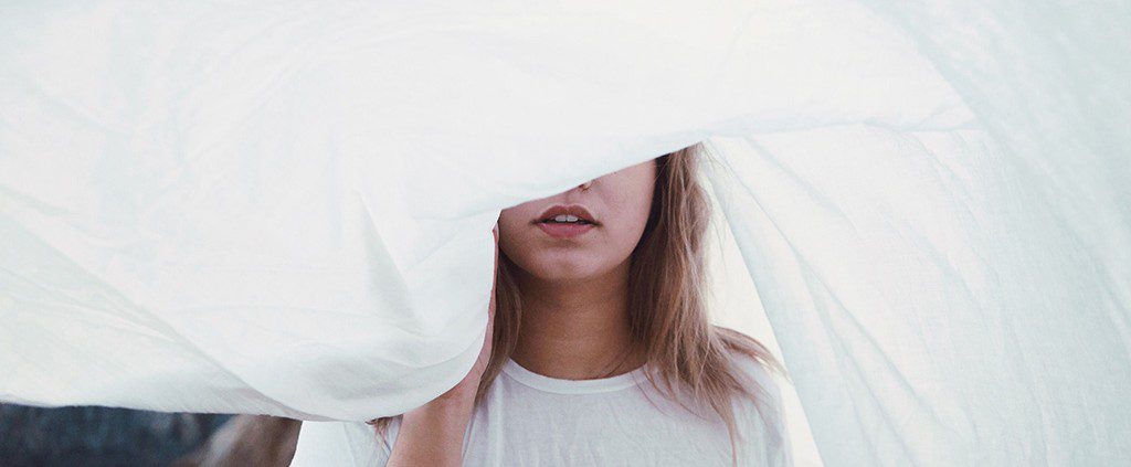 Woman with a white sheet waving over her face