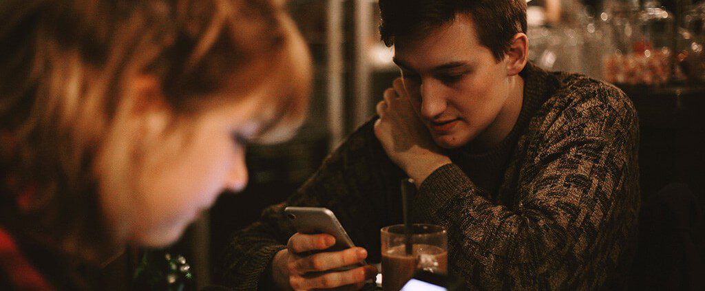 Guy on his phone sitting at a table with friends