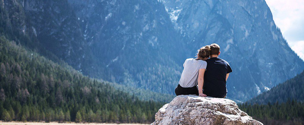Couple sitting on a rock looking at mountains together