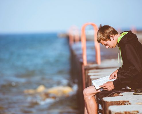 Boy sitting on a dock reading