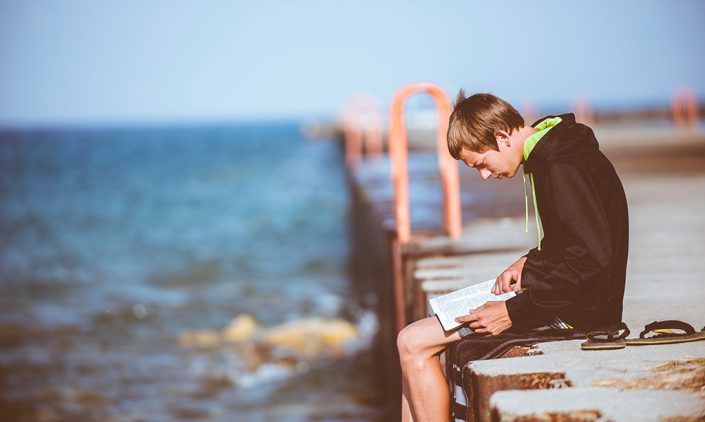Boy sitting on a dock reading