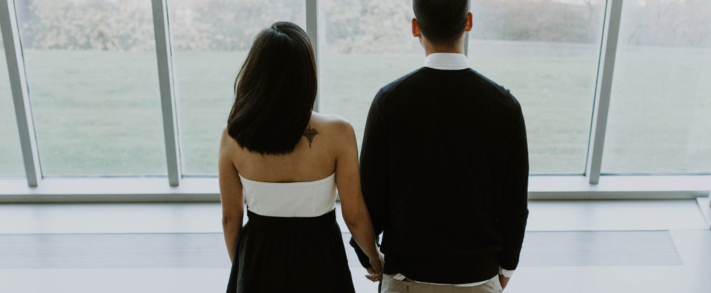 Couple holding hands looking out of windows