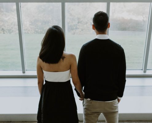 Couple holding hands looking out of windows