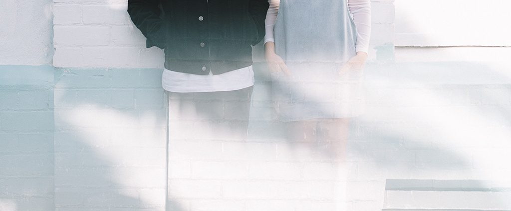 Couple standing next to each other against a wall