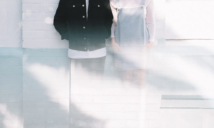 Couple standing next to each other against a wall