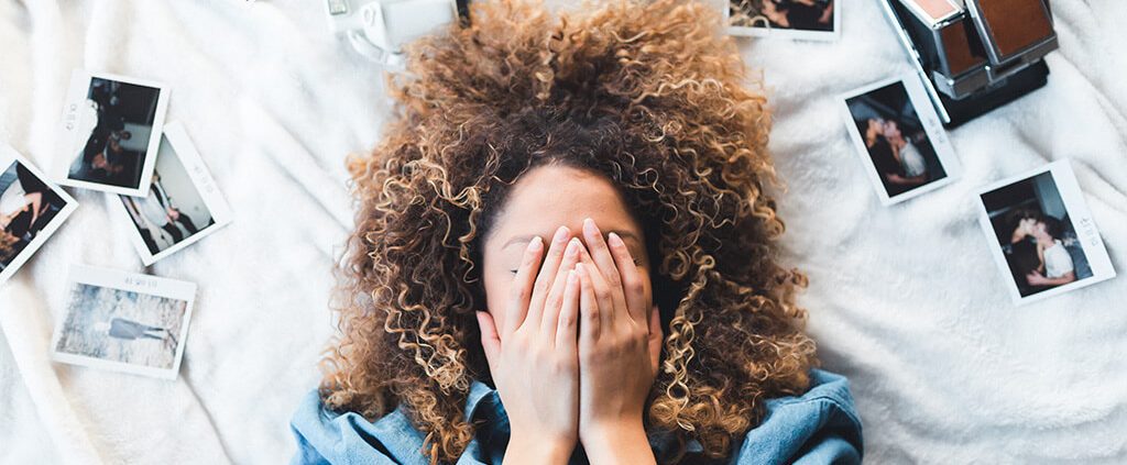 Woman holding her hands over her face in bed