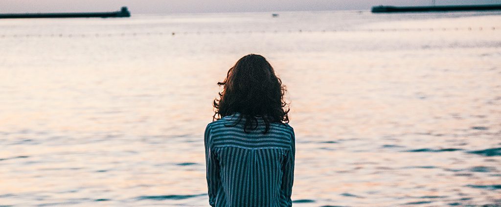 Woman sitting alone looking out over the water