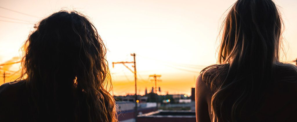 Two sisters sitting together watching the sunset