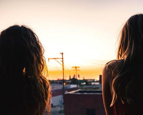 Two sisters sitting together watching the sunset
