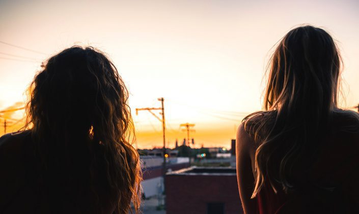 Two sisters sitting together watching the sunset