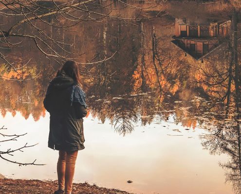 Woman alone pondering deeply looking at a pond