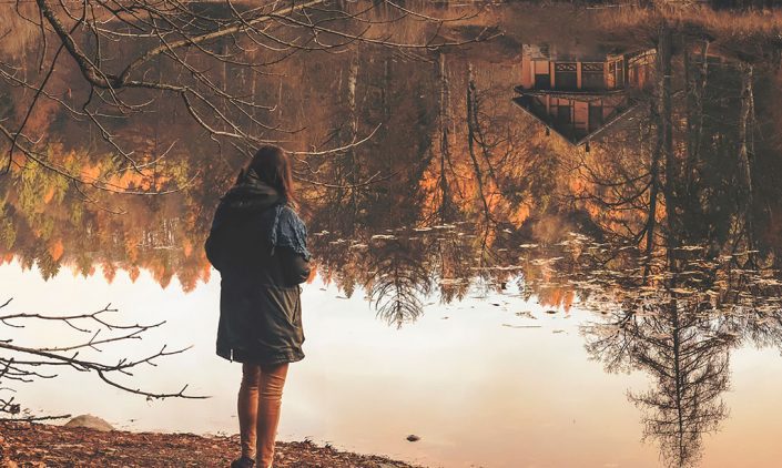 Woman alone pondering deeply looking at a pond