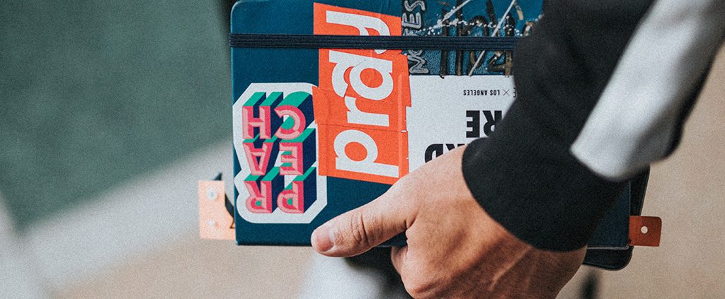 Man holding a notebook with stickers on it