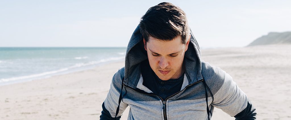 Man walking on the beach alone somberly