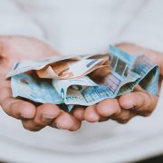 Hand holding dollar bills - stewardship is not just about money
