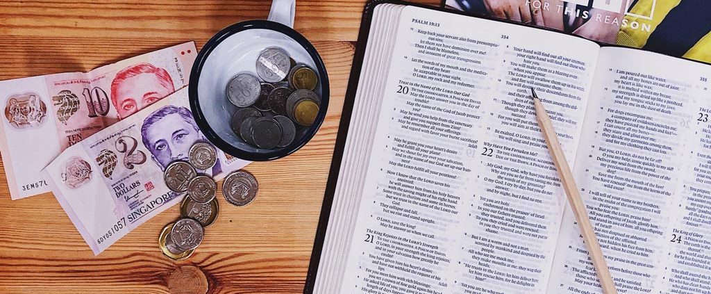 Open Bible next to a table full of money