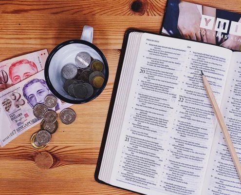 Open Bible next to a table full of money