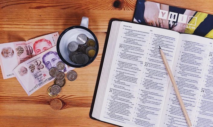 Open Bible next to a table full of money