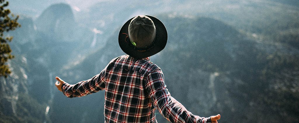 Man with his arms wide open on top of a mountain