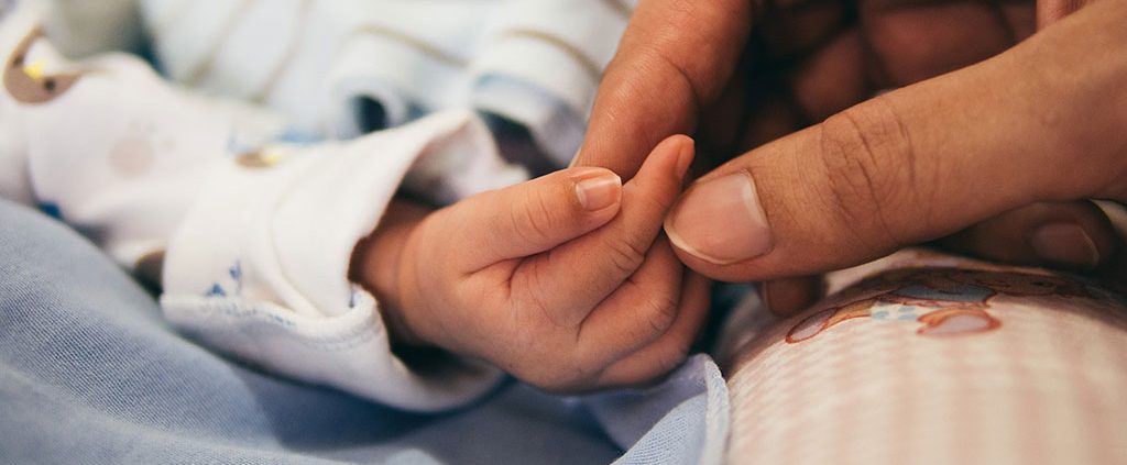 A parent holding their babies hand