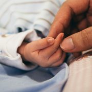 A parent holding their babies hand