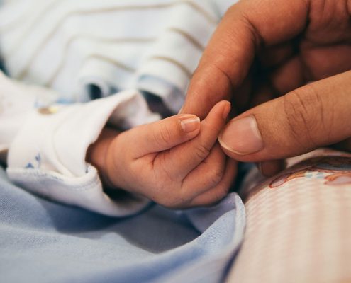 A parent holding their babies hand