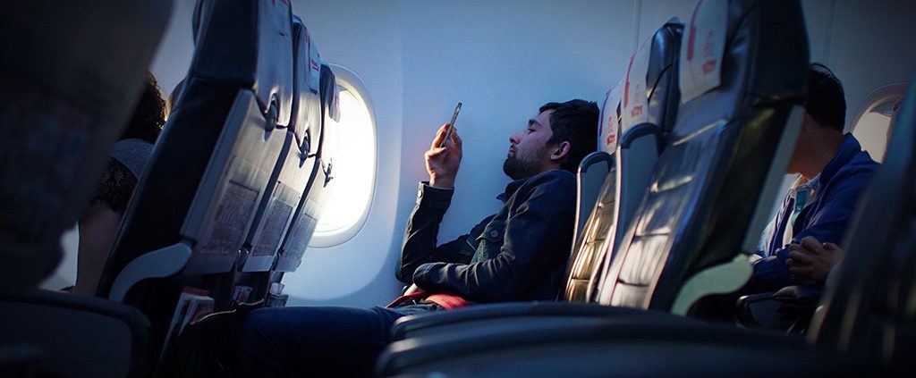 Man scrolling on his phone while flying