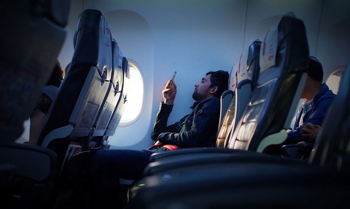Man scrolling on his phone while flying