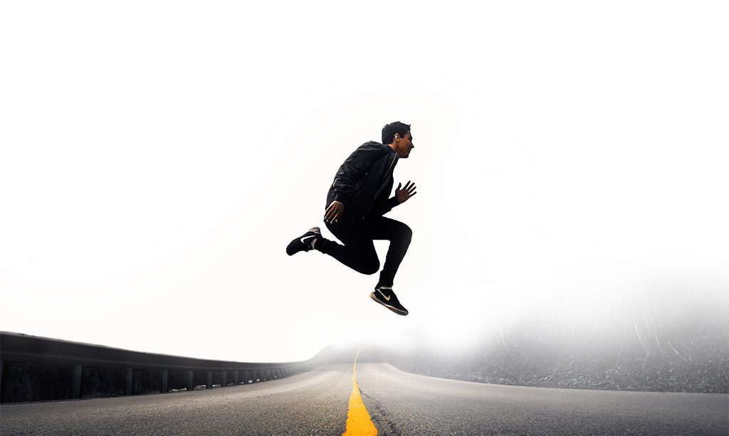 Man jumping up on an abandoned road