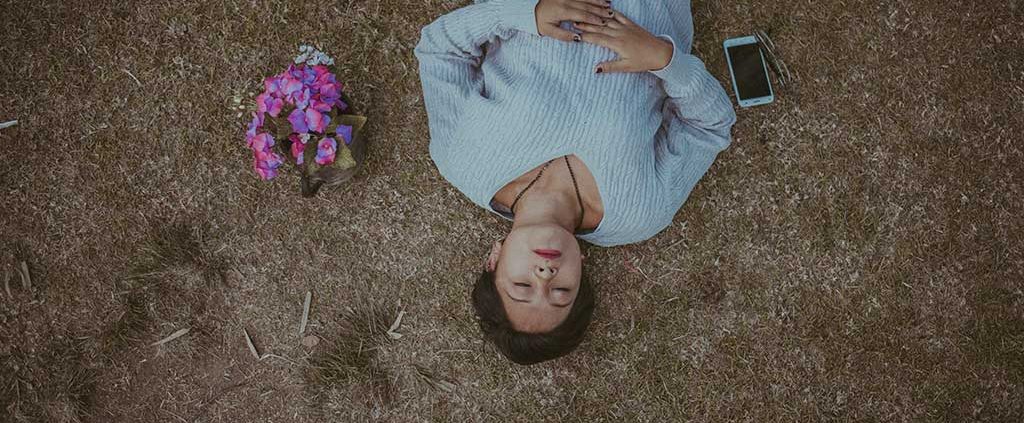 Girl lying down with flowers in a grass field