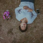 Girl lying down with flowers in a grass field