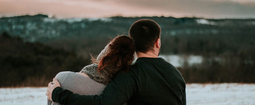 Couple sitting together looking at snow-filled mountains