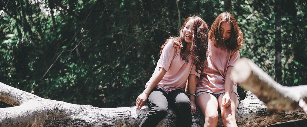 Two girls laughing sitting on a log