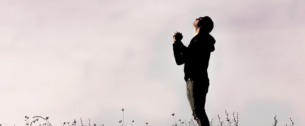 Man standing in a field praying