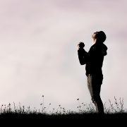 Man standing in a field praying